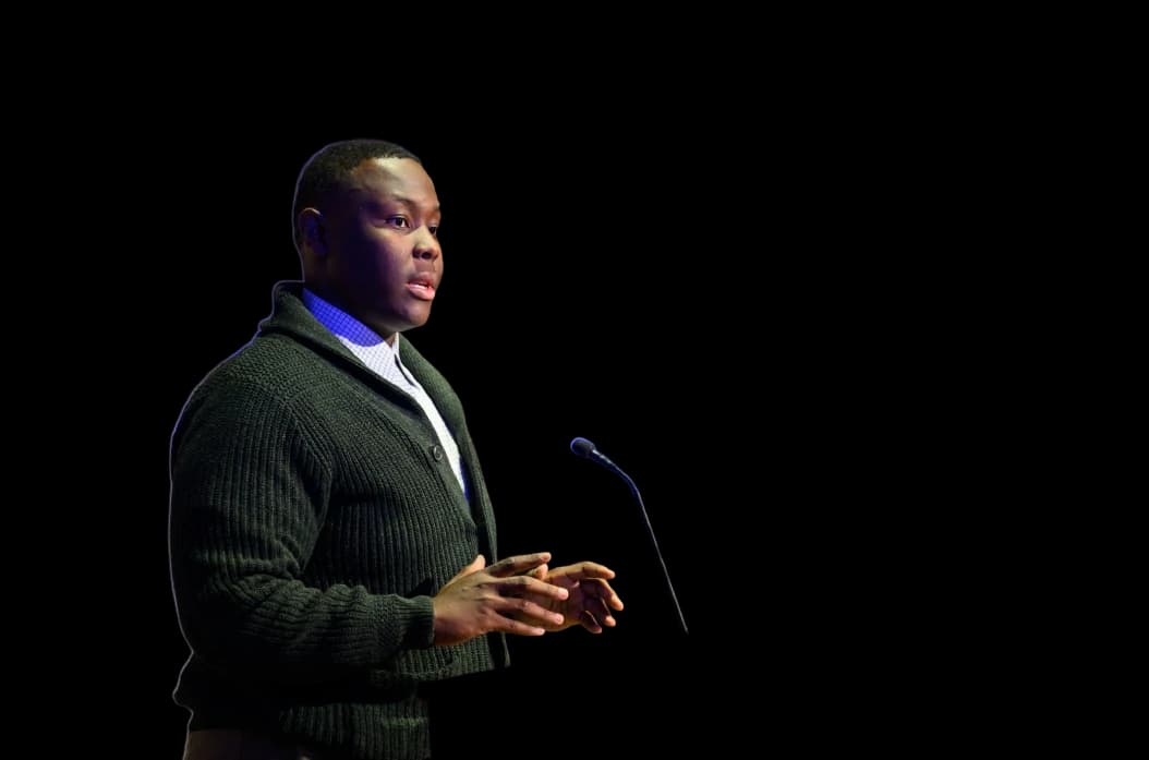 Caleb Jakes speaking into a handheld microphone